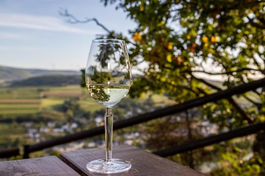 Glas of white wine at a scenic point near Brauneberg on river Moselle with view of landscape in the background