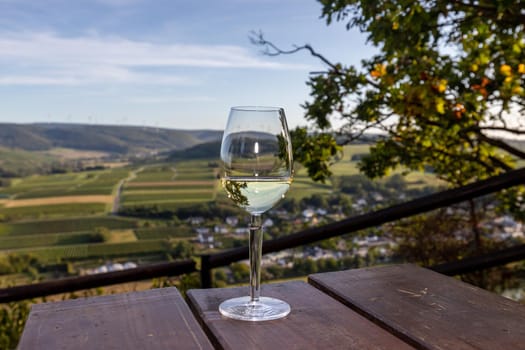 Glas of white wine at a scenic point near Brauneberg on river Moselle with view of landscape in the background