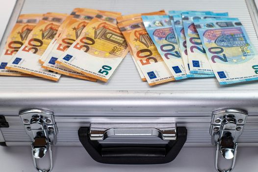 50 and 20 euro banknotes on aluminum briefcase on white background