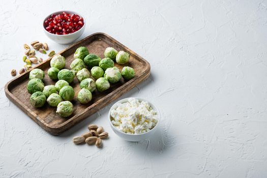 Brussels sprouts with pomegranate, cottage cheese and pistachios, on white textured background with space for text