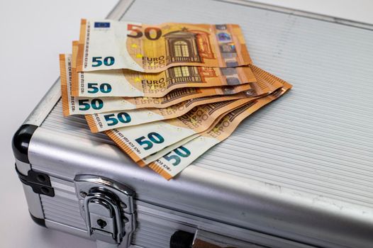 euro banknotes on aluminum briefcase on white background