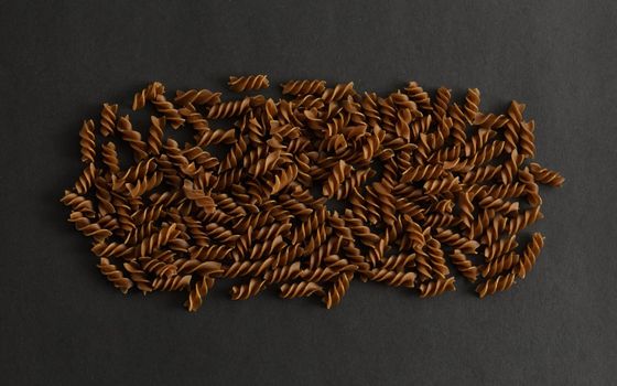 Top view of dark buckwheat pasta in dark key. High quality photo