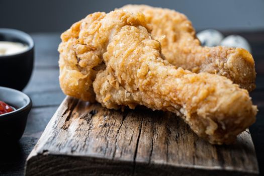 Fried crispy chicken legs, drumstick parts on dark wooden background.