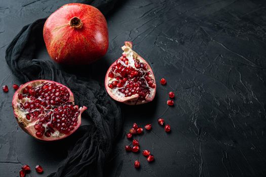 Ripe pomegranate with juicy seeds, on black textured background with space for text