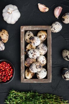 Quails eggs, top view, on black textured background