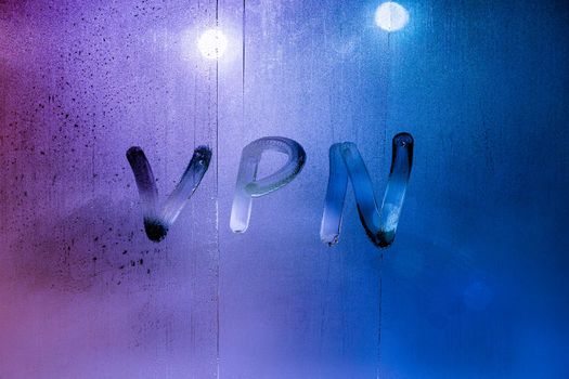an abbreviation VPN - virtual private network drawed by finger on night wet glass.