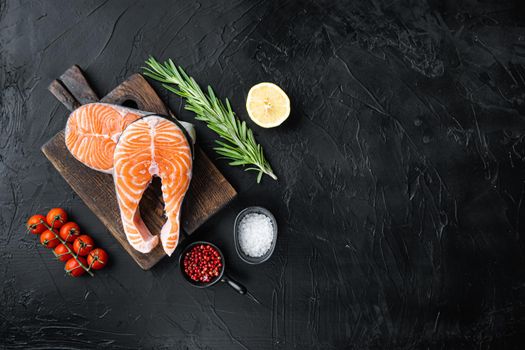 Slice of red fish salmon with herbs, over black background, flat view with space for text.