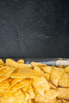 Nachos, triangle traditional Mexican corn appetizer pack, on black background, top view or flat lay with copy space for text