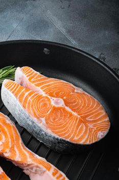 Raw trout steak on grill skillet, over grey background.