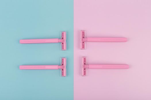 Top view of pink plastic razors on pink and blue background. High quality photo