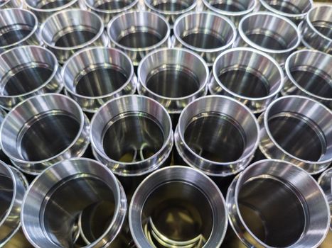 dark industrial background with cnc machined shiny silver colored steel pipes - selective focus and lens blur technique