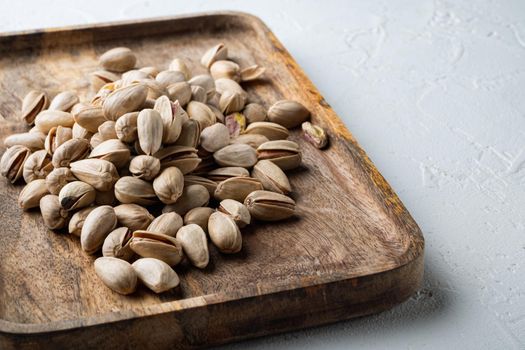 Shelled, unsalted pistachios, on white textured background
