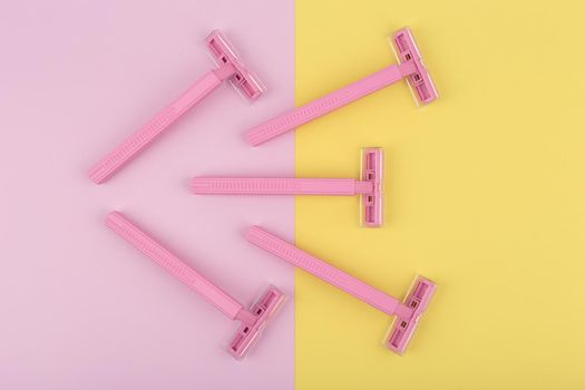 Top view of pink razors for shaving on colored duotone yellow and pink background. Concept of hygiene and tools for smooth skin