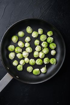 Raw brussels sprouts, on black textured background, flat lay