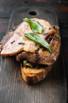 Liver bacon and onions on bread cooked meal served on board, over wooden background.