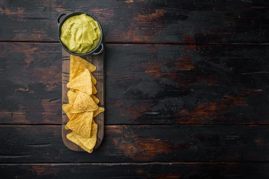 Triangular yellow corn tortilla chip with sauces, on old wooden table, top view or flat lay with copy space for text