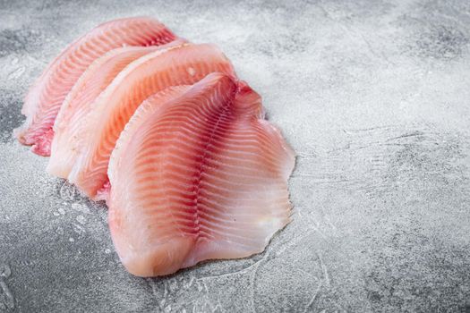 Tilapia fish, skinless meat, on gray background with copy space for text