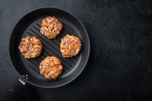 Raw quick asian salmon cutlet, on black textured background, top view with space for text
