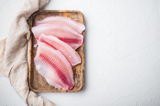 White tilapia fish fillet cuts on white background, top view with copy space for text