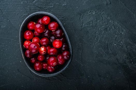 Cranberry, ripe red berry in bowl, flat lay with space for text, on black background.