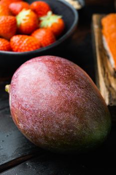 Whole exotic mango on dark wooden background.