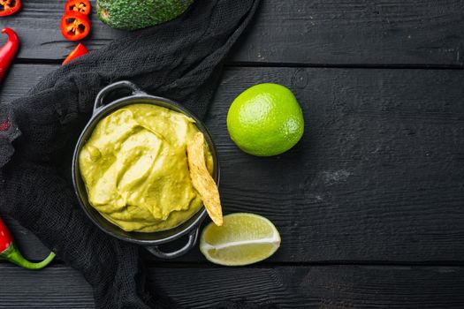 Avocado guacamole sauce in bowl, on black wooden background, top view or flat lay with copy space for text