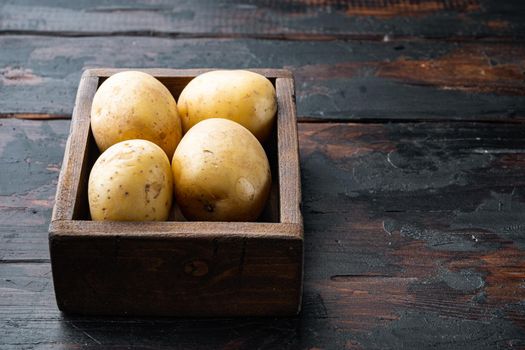 Several tuber of raw potatoes, on old wooden table with space for text