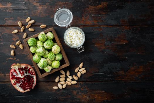 Brussels sprouts with pomegranate, cottage cheese and pistachios, on old wooden table, flat lay with space for text