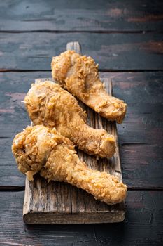 Breaded kentucky chicken drumctick parts on old dark wooden table.