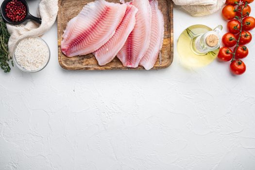 Raw white fish tilapia, with basmati rice and cherry tomatoes ingredients, on white background, top view with copy space for text
