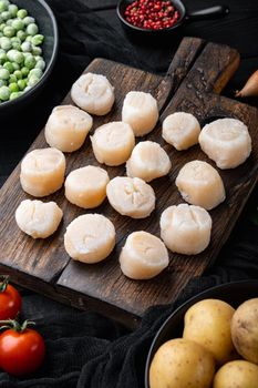 Fresh raw scallops ingredients ready for cooking, on black wooden background