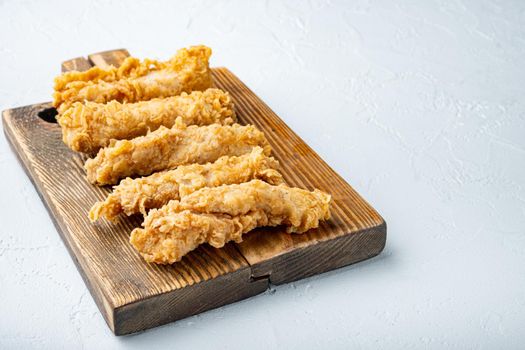 Fried crispy chicken stripes parts on white background.