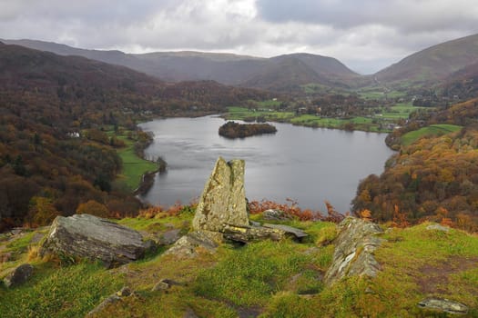 View climbing up Loughrigg Fell over the lake of Grasmere with the fells behind under a stormy sky, Lake District, UK