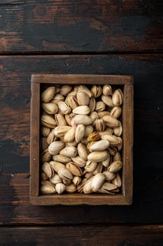 Shelled, unsalted pistachios, on old wooden table, flat lay