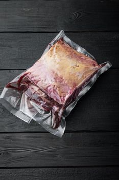 New York beef steak huge cut in plastic pack, on black wooden table, top view, with copy space for text