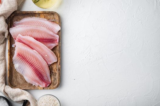 Raw white fish tilapia, with basmati rice and cherry tomatoes ingredients, on white background, top view with copy space for text