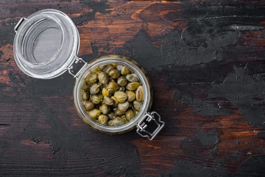 Baby capers in marinate glass jar, on old wooden table, top view with copy space for text