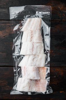 Haddock fish skinless in vacuum package, on dark wooden background, top view