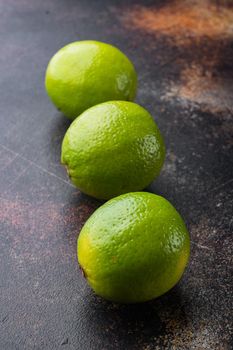 Whole green lime set, on old dark rustic background