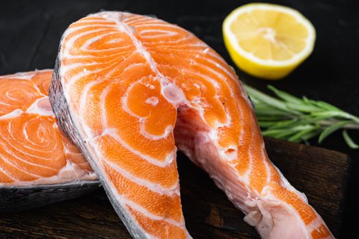 Salmon steak raw fish with herbs, over black background.