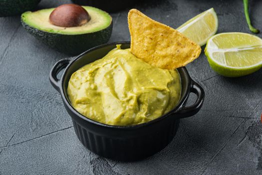 Bowl with guacamole made of ripe avocado, on gray background