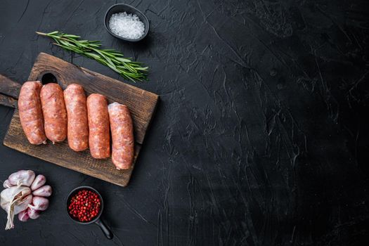 Raw organic pork sausages, top view with space for text, on black background.