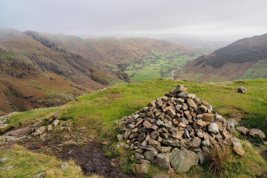 View over a large cairn down the valley of Great Langdale on the way up Loft Crag in the Langdale Pikes, Lake District, UK