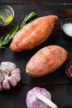 Sweet potato or batat with herbs on old wooden table, top view.