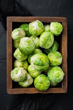 Raw brussels sprouts, on black textured background, flat lay