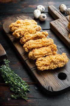 Fried chicken wings parts on dark wooden background.