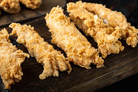 Deep fried crunchy spicy chicken meat on dark wooden background.