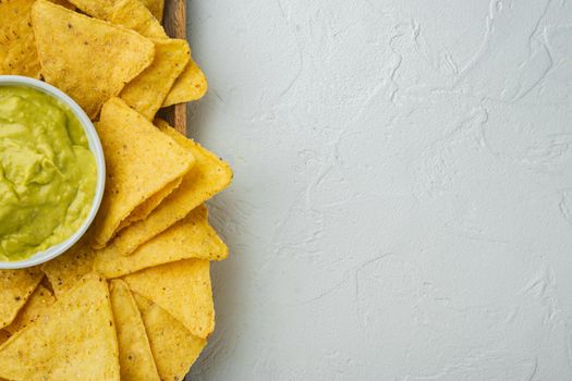 Mexican nachos chips with cheese and guacamole sauces, on white background, top view or flat lay with copy space for text