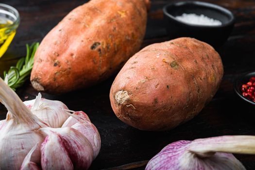 Sweet potato or batat with herbs on old wooden table.