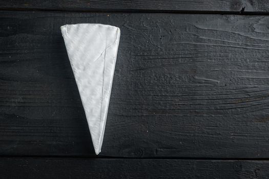 Delicious brie cheese piece, on black wooden background, top view with copy space for text